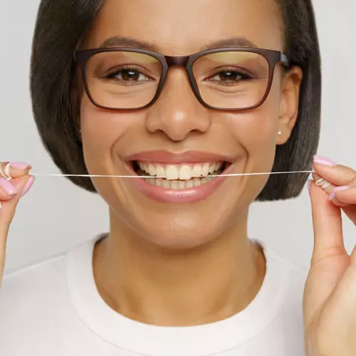 happy-female-flossing-teeth-with-dental-thread happy-female-flossing-teeth-with-dental-thread